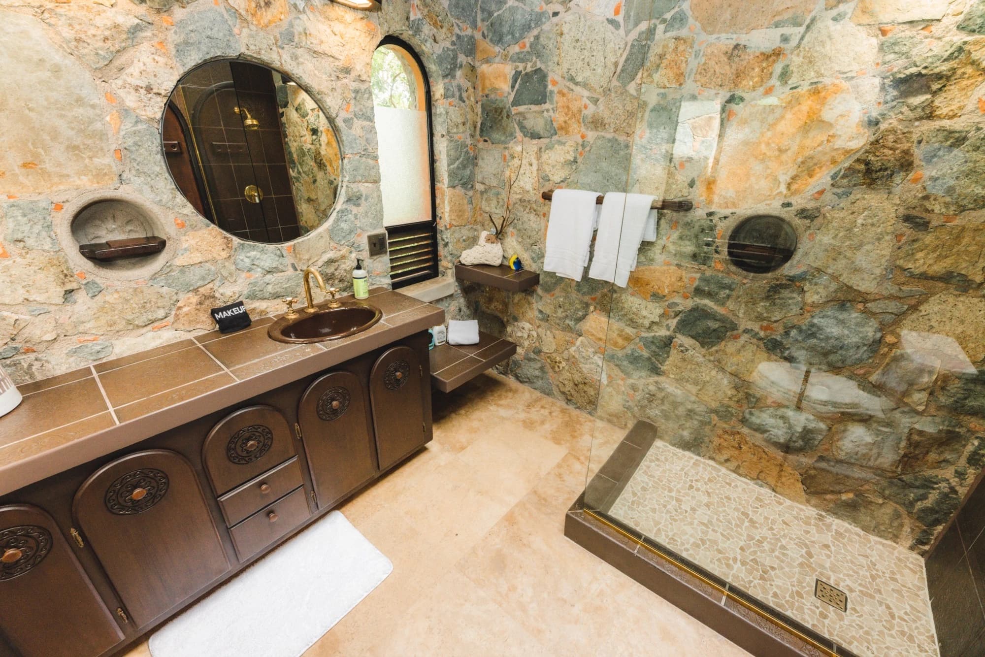 Stone bathroom with ornate vanity and porthole windows at Valhalla St John