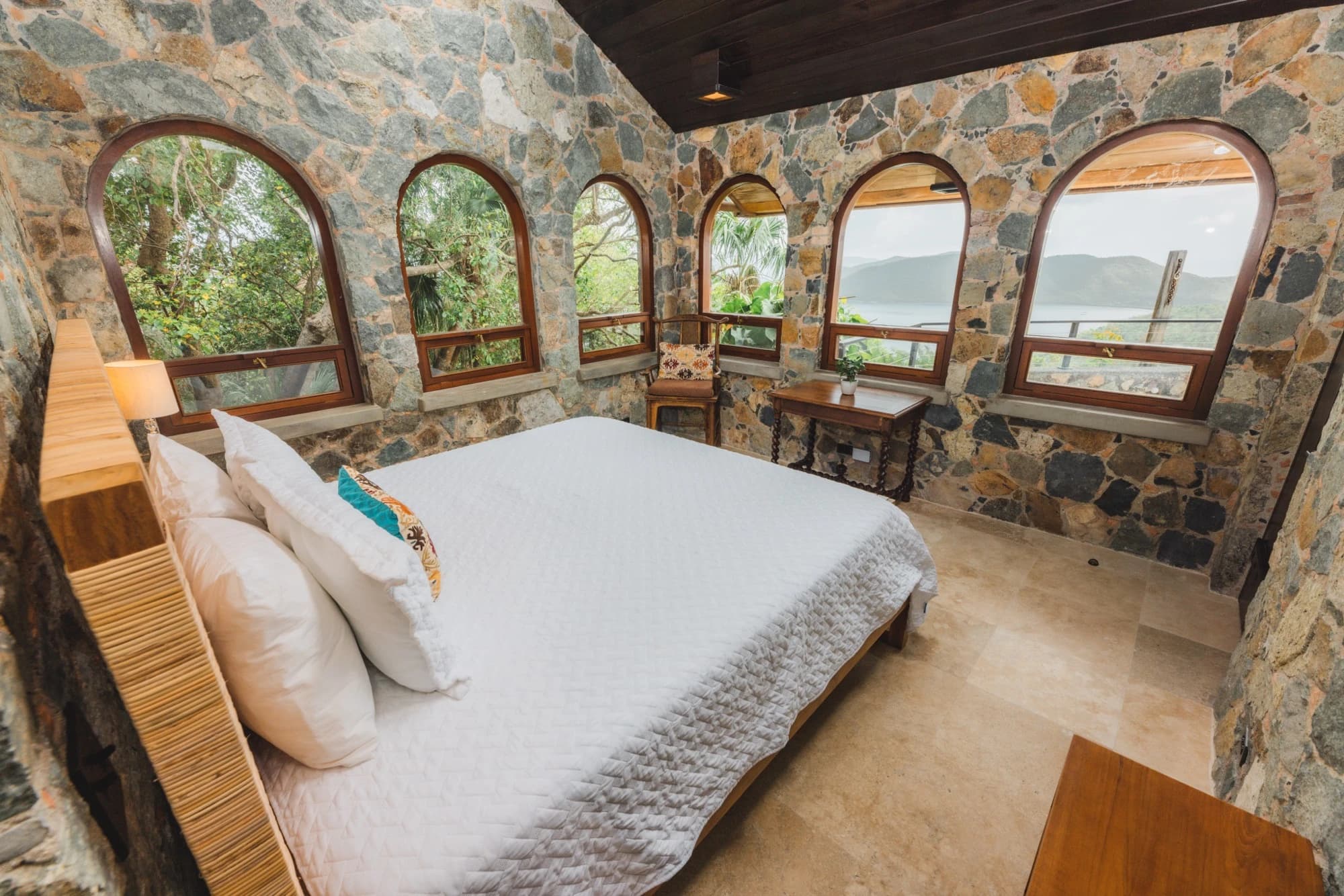 Bedroom with ocean views through arched stone windows at Valhalla St John villa