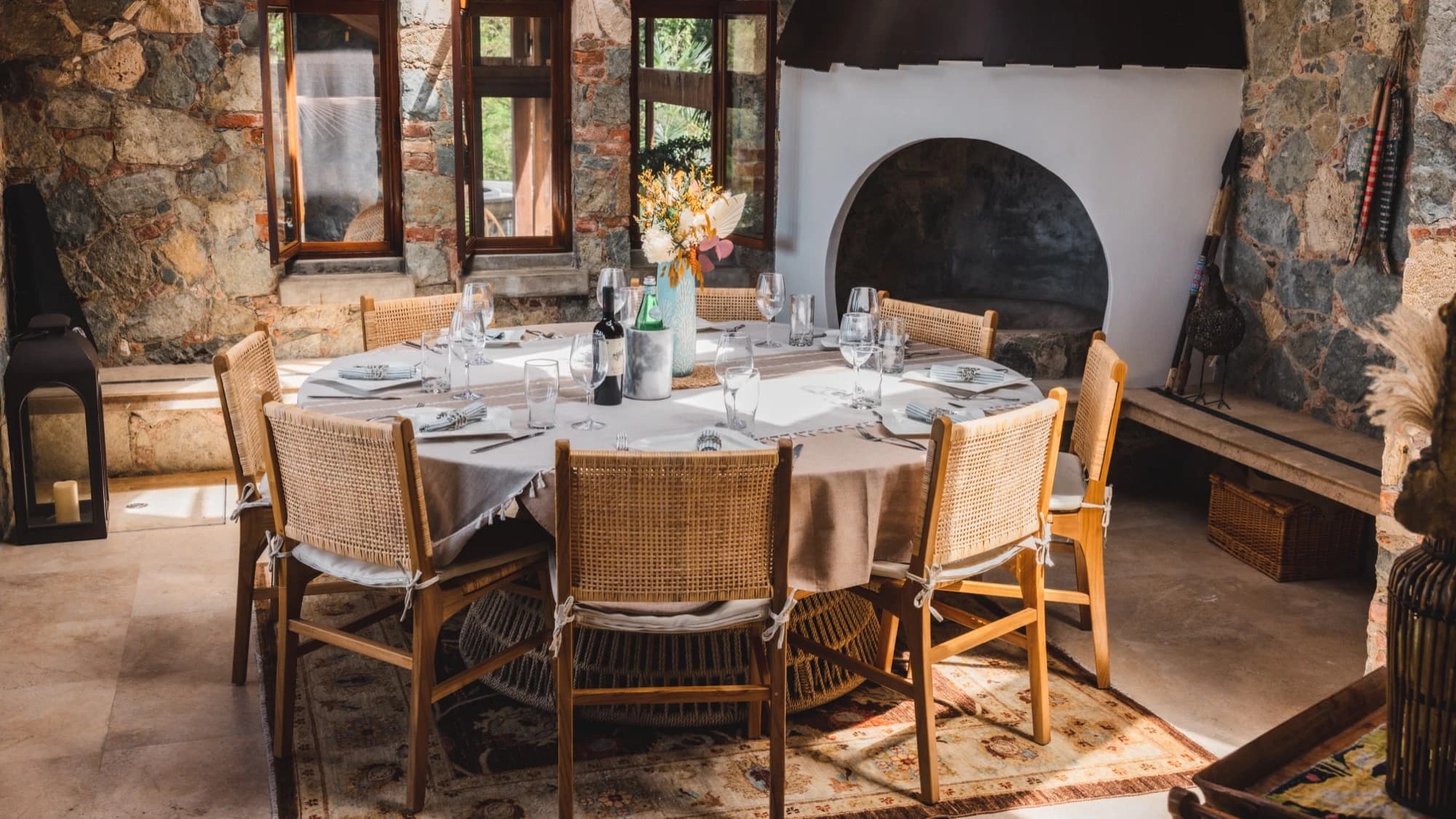Round dining table set for dinner with stone fireplace at Valhalla St John villa